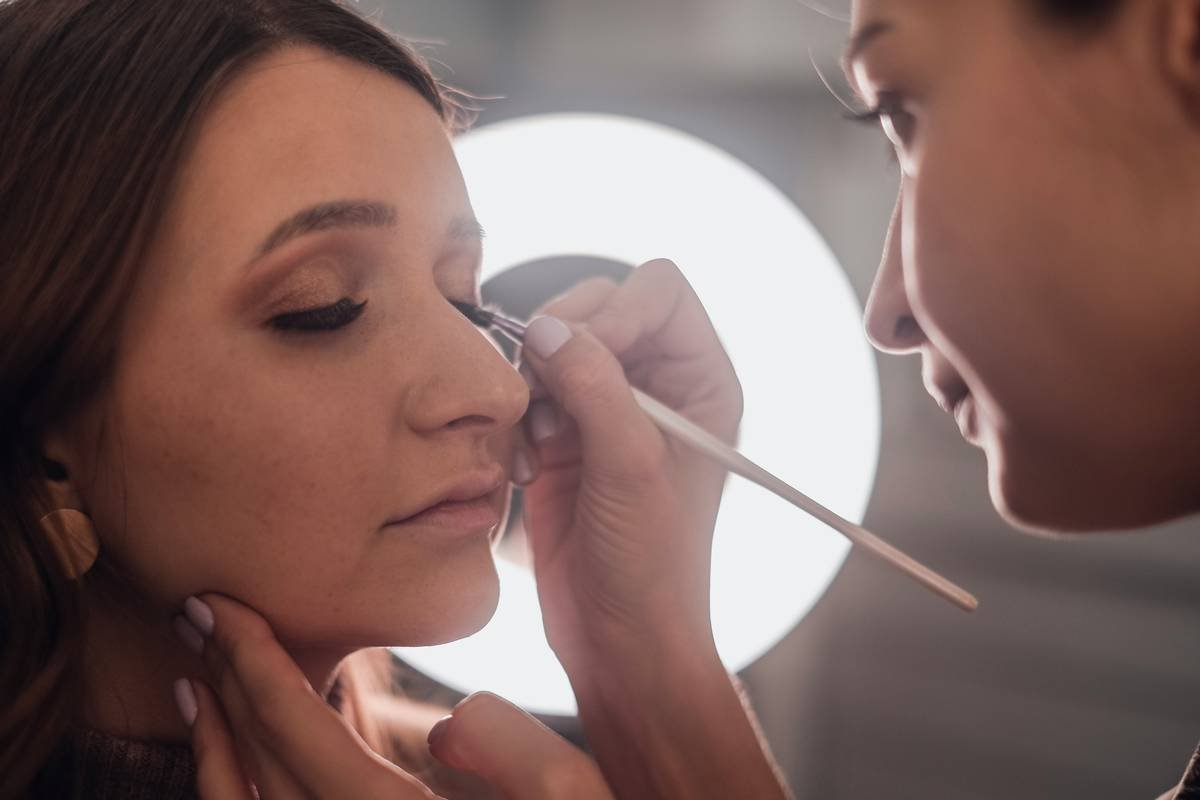 woman putting eyeliner on another woman's eye